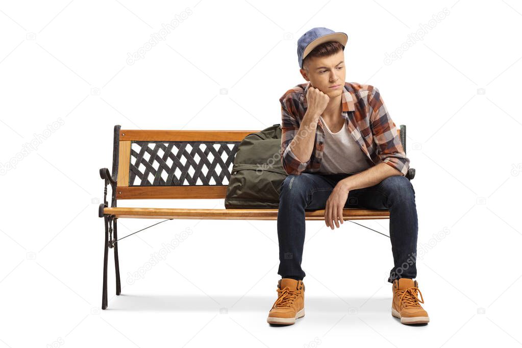 Worried young male student sitting on a bench and looking away