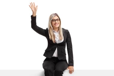 Sarışın iş kadını panelde oturmuş el sallıyor.