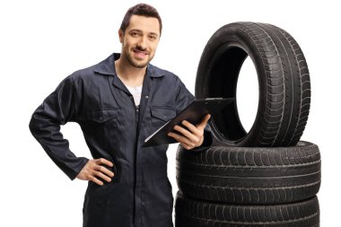 Young mechanic standing next to vehicle tires with a clipboard 
