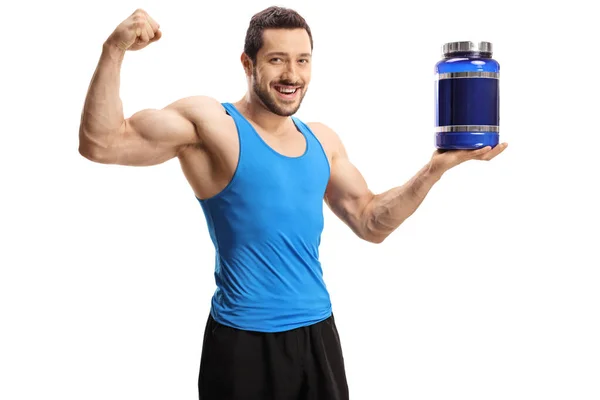 Young bodybuilder holding a pack of protein powder and flexing b — Stockfoto