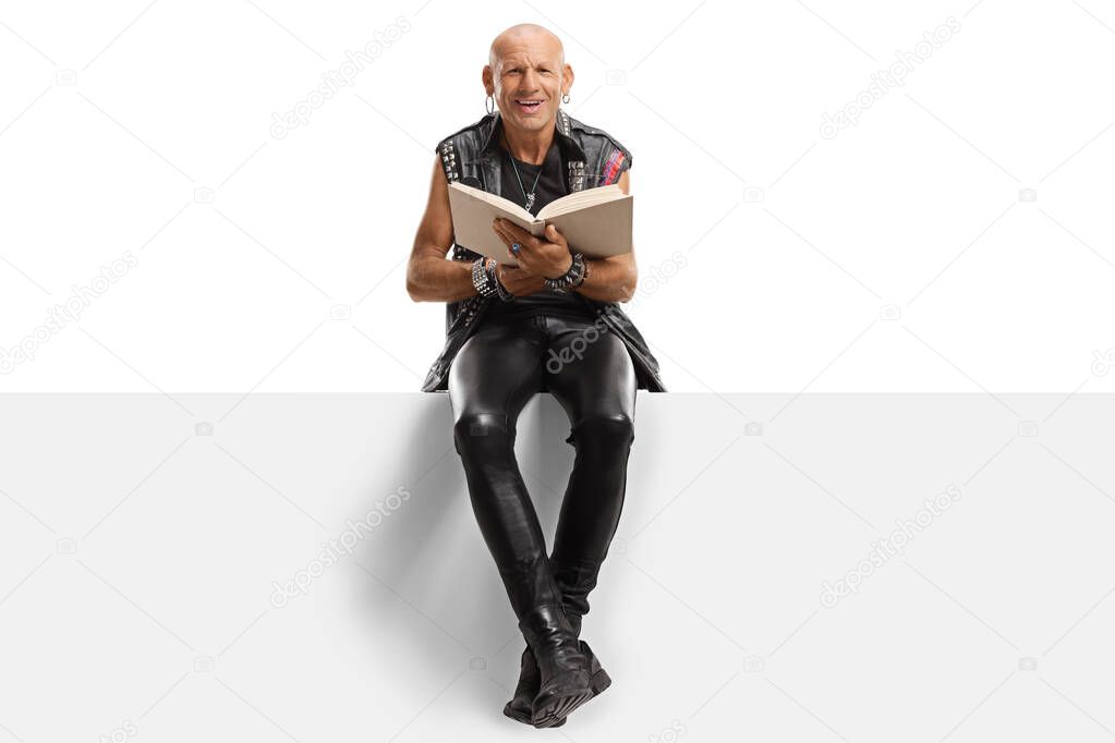 Punk sitting reading a book on a panel and smiling at the camera