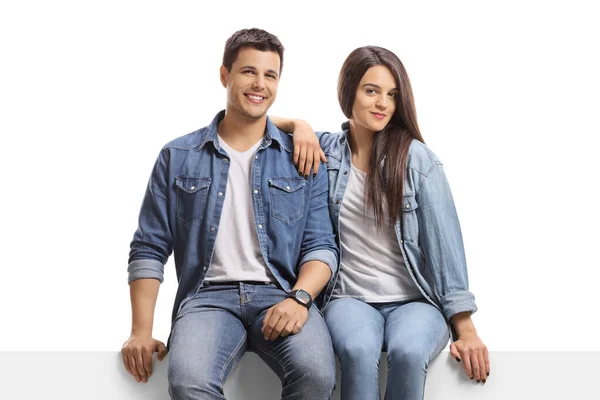 Jovem homem e mulher em jeans sentado em um painel e olhando para — Fotografia de Stock