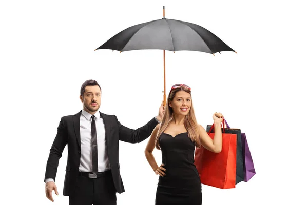 スーツの男は白い背景に隔離されたショッピングバッグを持つ若い女性の上に傘を保持 — ストック写真
