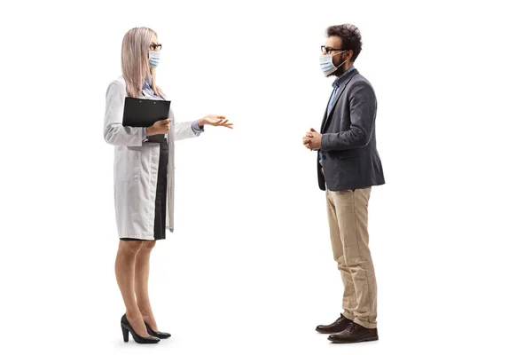 一名戴防护面罩的女医生与一名戴防护面罩 背景为白色的男子交谈时的全长照片 — 图库照片
