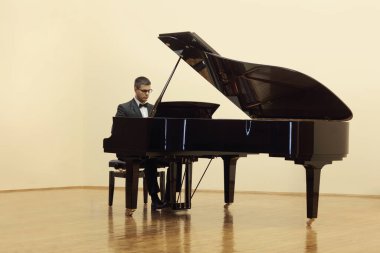 Beyaz arka planda izole edilmiş bir salonda piyano çalan piyanist.