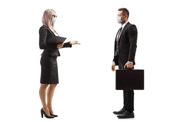 Full length profile shot of a businesswoman talking to a businessman and wearing protective face masks isolated on white background