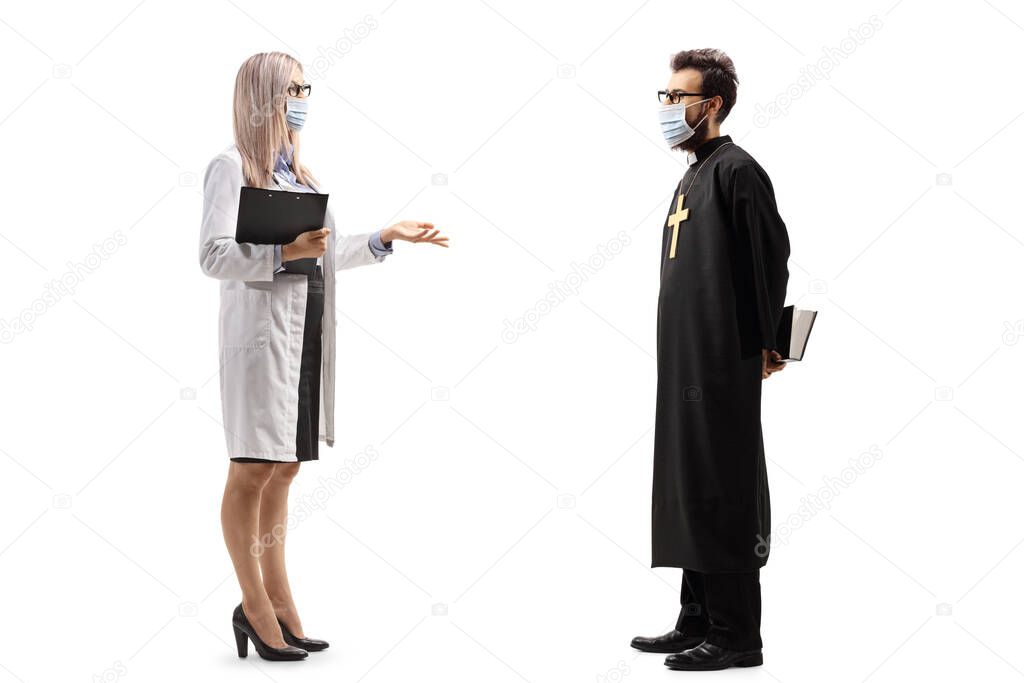 Full length profile shot of a female doctor with a protective mask talking to a priest isolated on white background