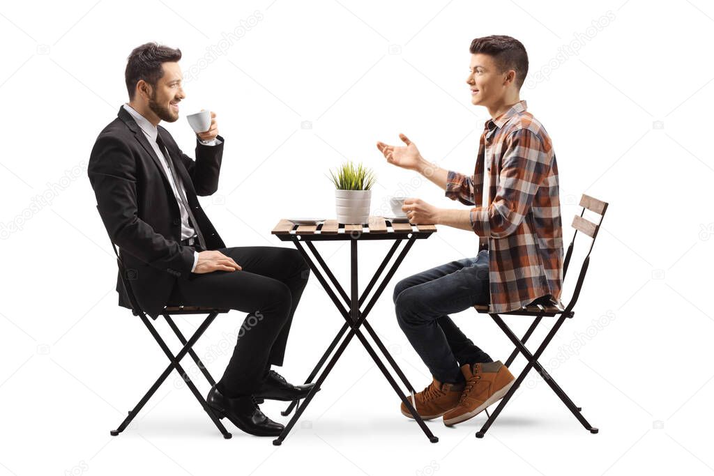 Male student sitting at a wooden table and talking with a businessman isolated on white background