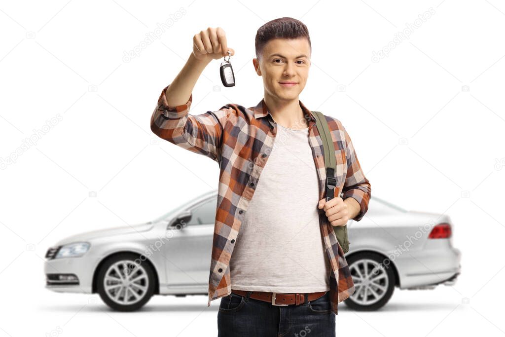 Male teenager holding a car key from his new silver car isolated on white background