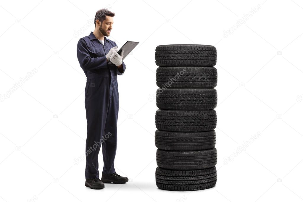 Auto mechanic worker in a uniform counting tires and writing a document isolated on white background