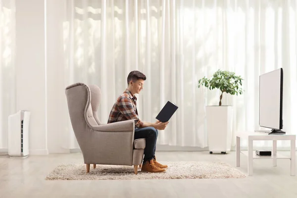 Profile Shot Young Man Sitting Armchair Reading Book Front Home — Stock Photo, Image