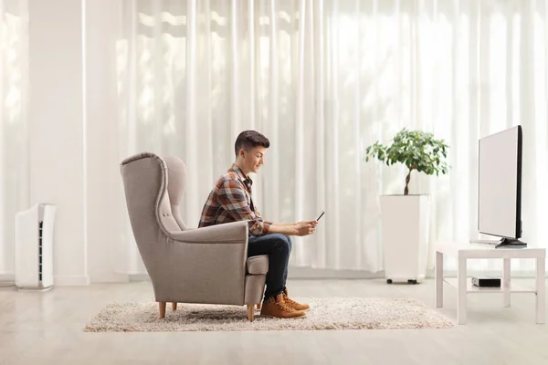 Man Zit Thuis Een Fauteuil Gebruikt Een Mobiele Telefoon Voor — Stockfoto