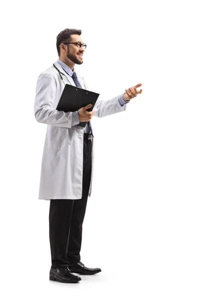 男医生拿着剪贴板用手在白色背景上做手势时的全长侧面照 — 图库照片