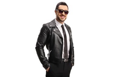 Siyah deri ceketli, güneş gözlüklü, beyaz arka planda yalnız poz veren yakışıklı bir genç.