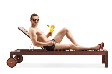 Mayo giymiş, güneşli bir yatakta uzanmış beyaz arka planda izole edilmiş bir kokteyl içen bir adamın tam boy fotoğrafı.