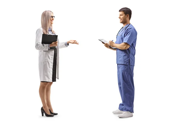 白地に隔離された会話を持っている女性と男性医師の完全な長さのプロフィールショット — ストック写真