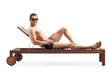 Beyaz arka planda izole edilmiş şezlongda güneşlenen zinde genç bir adam.