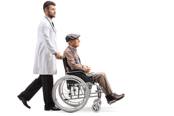 Young male doctor pushing a disabled elderly patient in a wheelchair isolated on white background