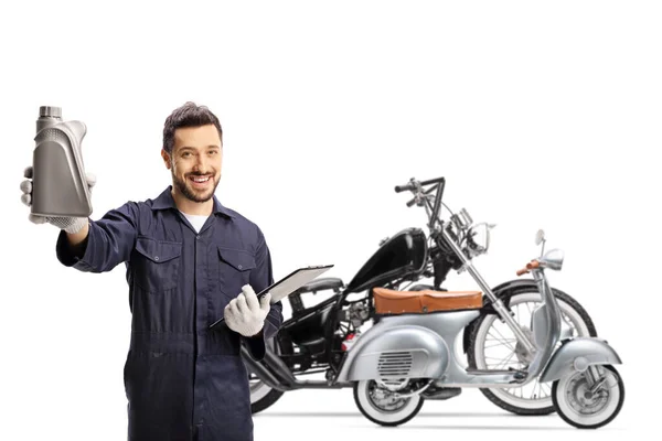 モーターオイルを保持し 白い背景に隔離されたチョッパーとスクーターの前に立っているバイク整備士 — ストック写真