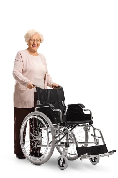 Starsza Kobieta Stojąca Pustym Wózkiem Inwalidzkim Odizolowanym Białym Tle — Zdjęcie stockowe