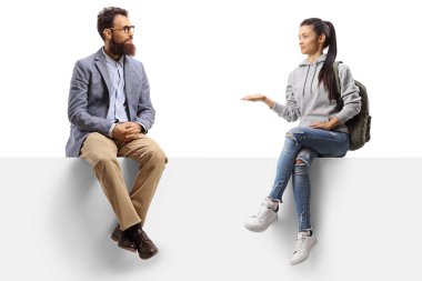 Panelde oturan ve beyaz arka planda sakallı bir adamla konuşan bir kız öğrenci.