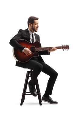 Elektrikli gitarlı bir müzisyen bir sandalyede oturuyor ve beyaz arka planda soyutlanmış bir şekilde çalıyor.