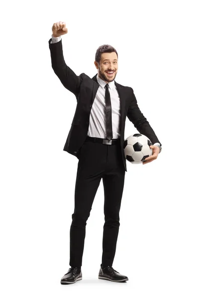 サッカーボールを持っている黒いスーツの男の完全な長さの肖像画と白い背景に隔離された幸福をジェスチャー — ストック写真
