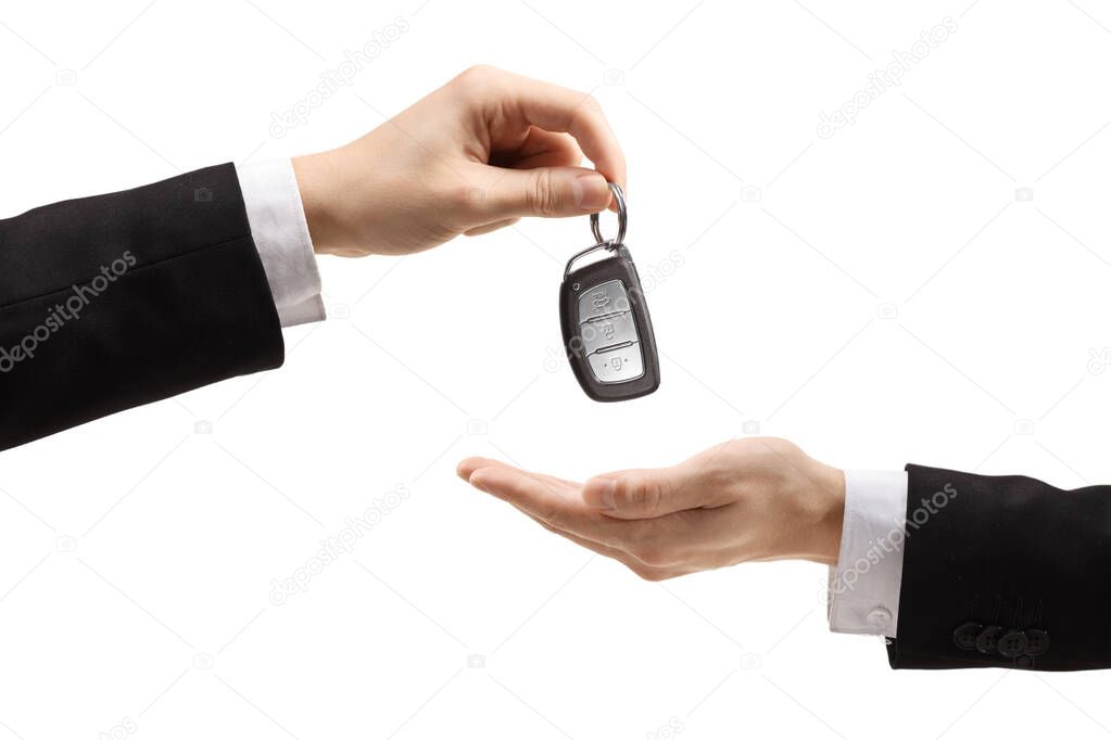 Male hand in a suit giving car keys to another male hand isolated on white background