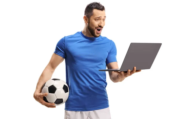 ボールを持っている興奮したサッカー選手と白い背景に隔離されたラップトップコンピュータを見て — ストック写真