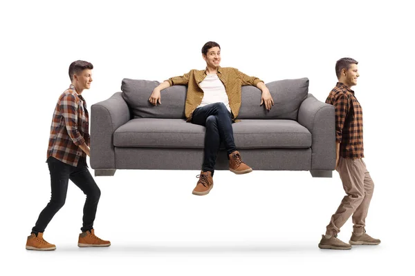 Mladí Muži Nesou Pohovku Mužem Který Sedí Izolovaný Bílém Pozadí — Stock fotografie