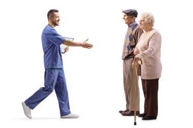 Beyaz arka planda el ele izole edilmiş yaşlı hastaları karşılayan bir erkek sağlık çalışanının tam boy profil fotoğrafı.