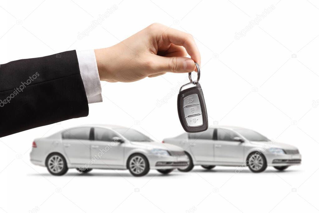 Two identical silver cars and a male hand holding a key isolated on white background