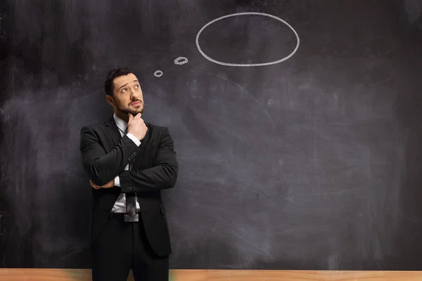 思考バブルを持つ黒板の前に立つスーツの男 — ストック写真