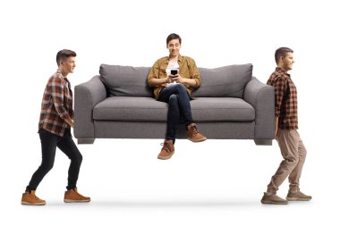 İki adam, beyaz arka planda izole edilmiş bir şekilde oturan ve cep telefonu kullanan bir adamla kanepe taşıyor.