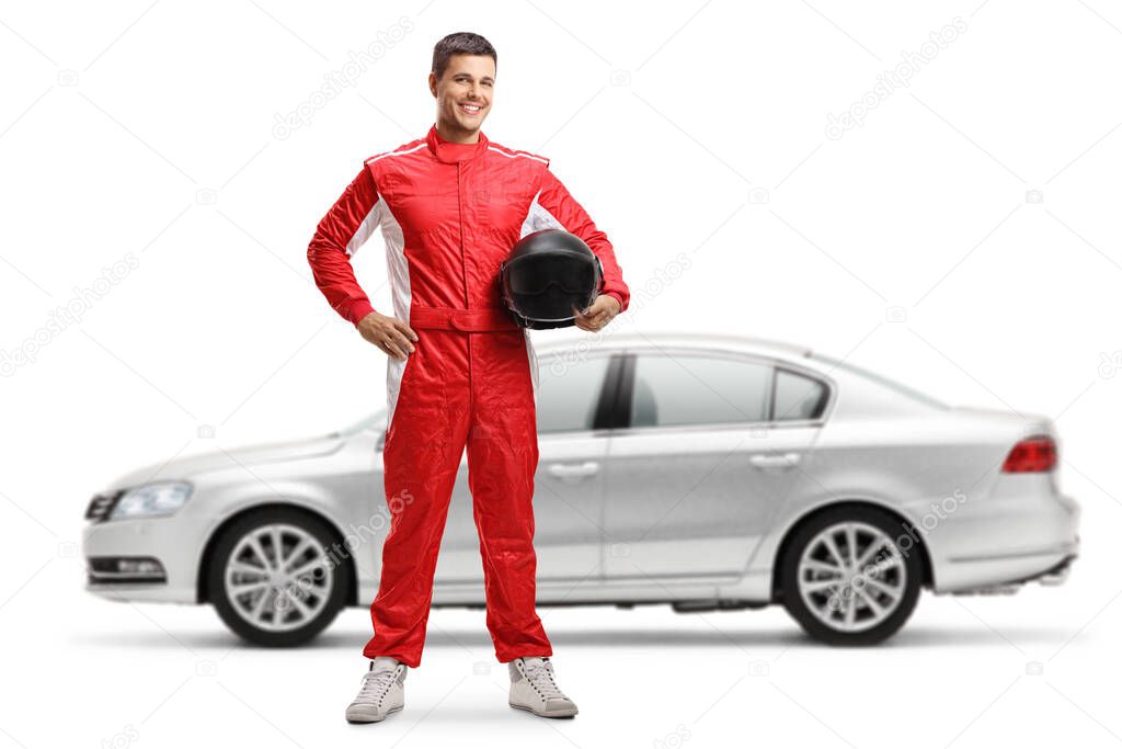 Full length portrait of a racer standing and holding a helmet in front of a silver car isolated on white background