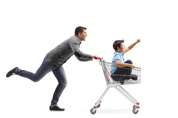 白い背景に隔離されたショッピングカートの中で少年を走らせて押す男 — ストック写真