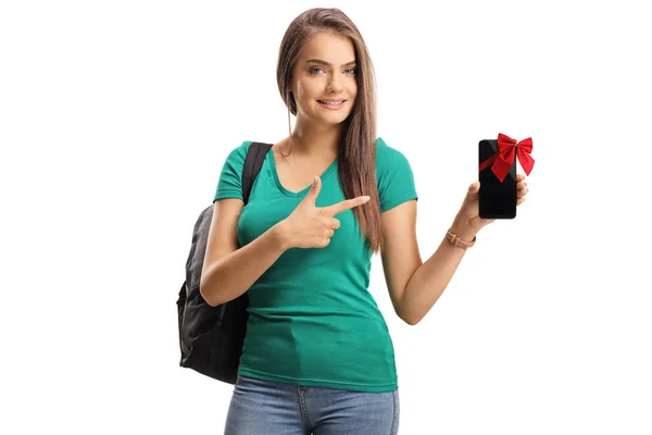 赤い弓と白い背景に隔離されたポインティングを持つスマートフォンを保持する女子学生 — ストック写真
