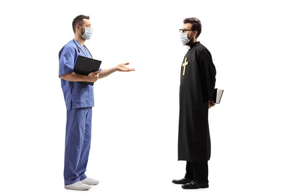 男性医師と僧侶の顔のマスクを着用し 白地に隔離された会話を持っているの完全な長さのプロフィールショット — ストック写真