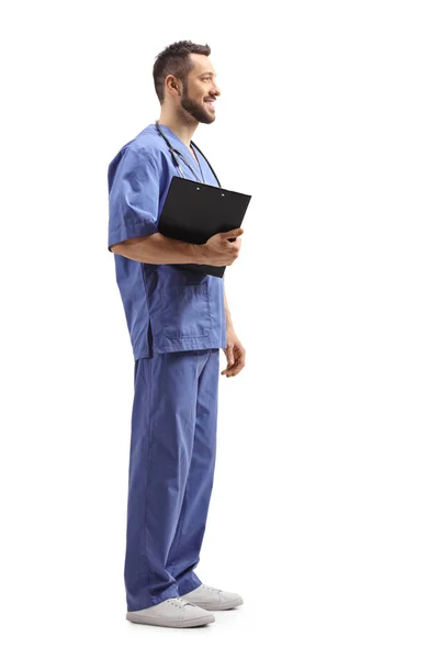 白い背景に隔離されたクリップボードを持つ男性医療従事者の完全な長さのプロフィールショット — ストック写真