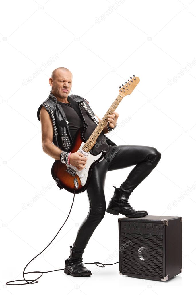 Full length shot of a rock star playing a guitar with his leg on an amplifier isolated on white background