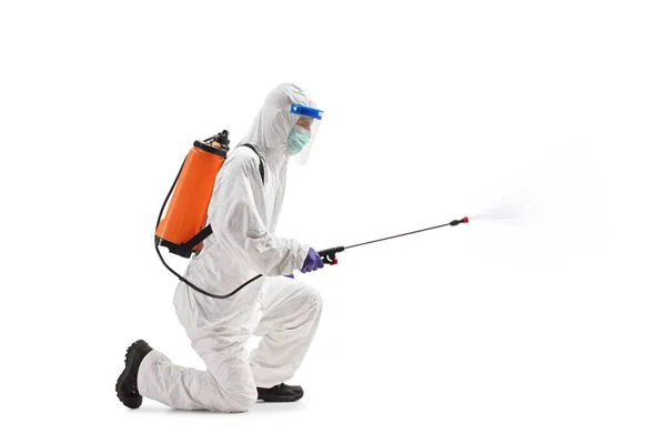 一名身穿危险垫套装的男子跪在地上 用白色背景隔离的消毒喷雾器拍摄的全长侧面照片 — 图库照片