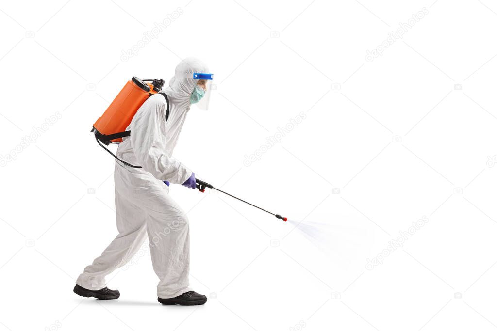 Full length profile shot of a man in a hazmat suit santizing with a spray isolated on white background