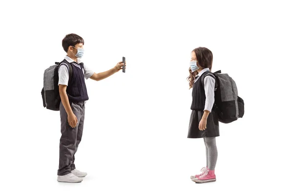 一名身穿防护面罩的男生的全长侧面照 并向一名身披白色背景的女生展示一部手机 — 图库照片