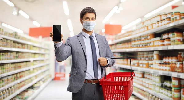 Homem Com Uma Cesta Compras Supermercado Mostrando Smartphone Usando Uma — Fotografia de Stock