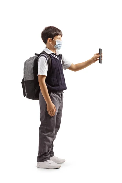 Pełna Długość Zdjęcia Ucznia Mundurze Maską Twarzy Pokazującą Smartfona Odizolowanego — Zdjęcie stockowe