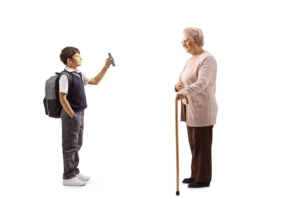 Pełna Długość Zdjęcia Ucznia Mundurze Stojącego Pokazującego Smartfona Staruszce Chodzącą — Zdjęcie stockowe