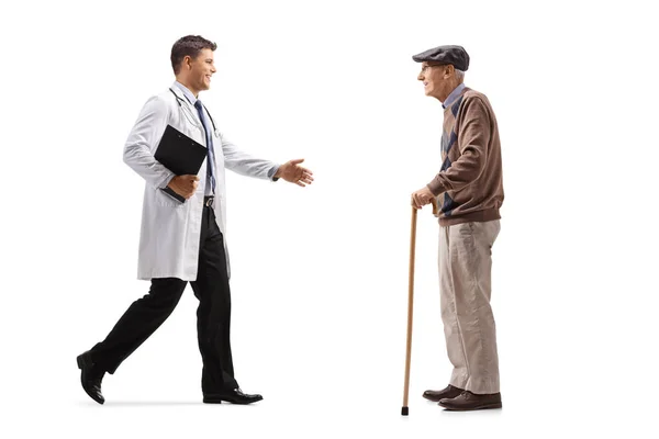 男性医師挨拶の完全な長さの肖像とともに手A高齢者男性とともに歩く杖白の背景に隔離 — ストック写真