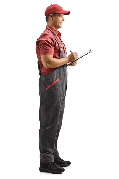 白い背景に隔離された文書を書く制服を着た男性労働者の完全な長さのプロフィールショット — ストック写真