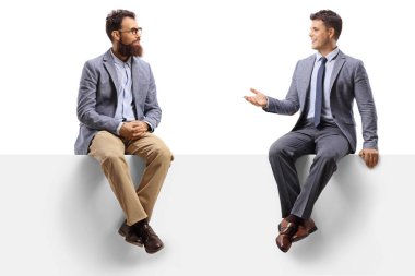 İki adam beyaz bir panelde oturuyor ve beyaz arka planda izole edilmiş bir şekilde sohbet ediyorlar.