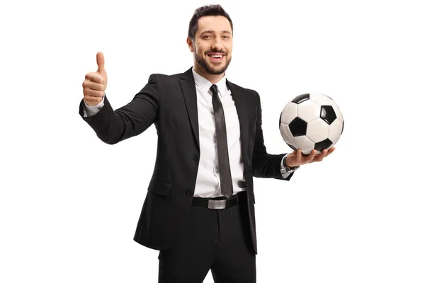 黒のスーツの男が親指を立てて白い背景に孤立したサッカーボールを保持 — ストック写真